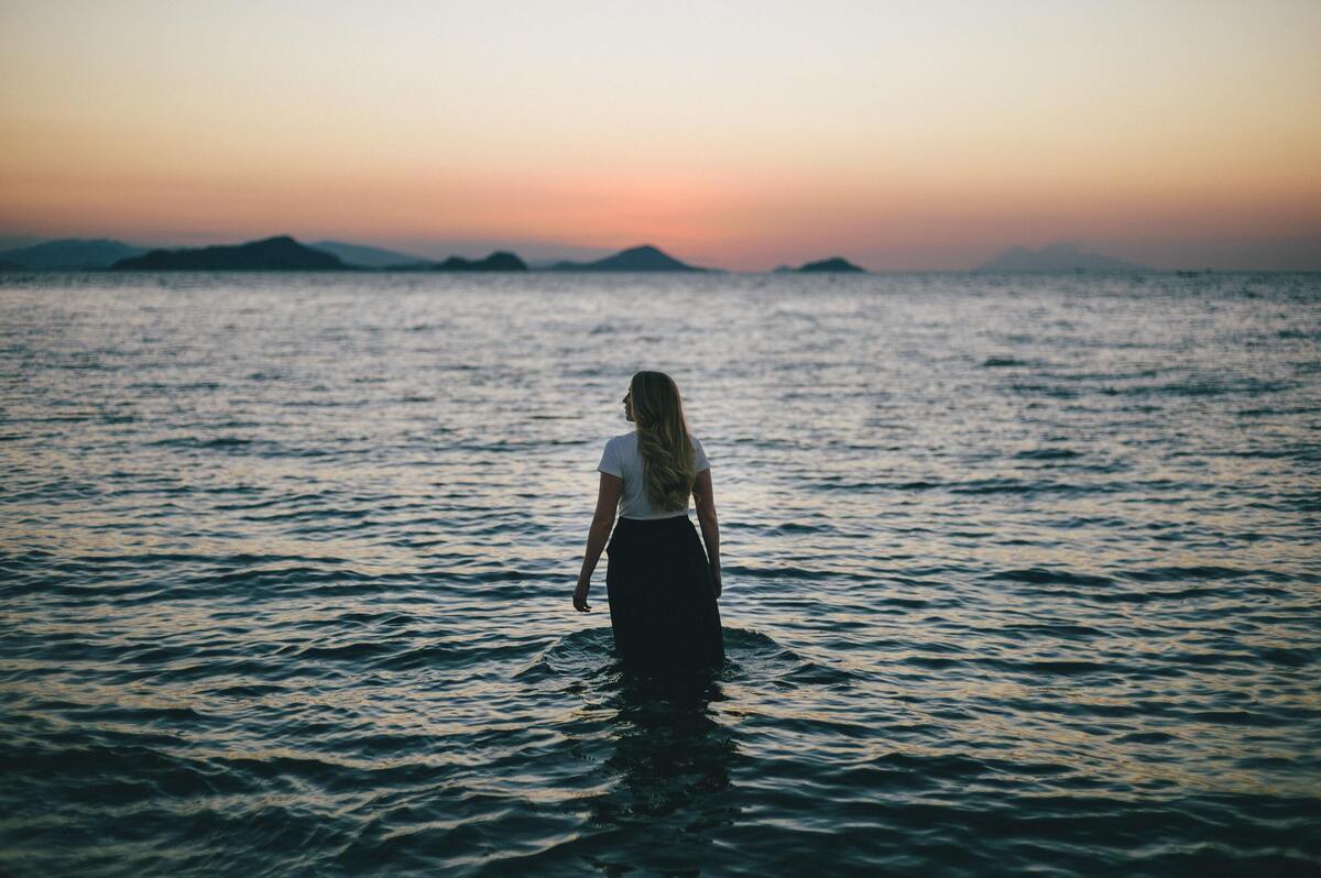 Menina em pé dentro do mar.