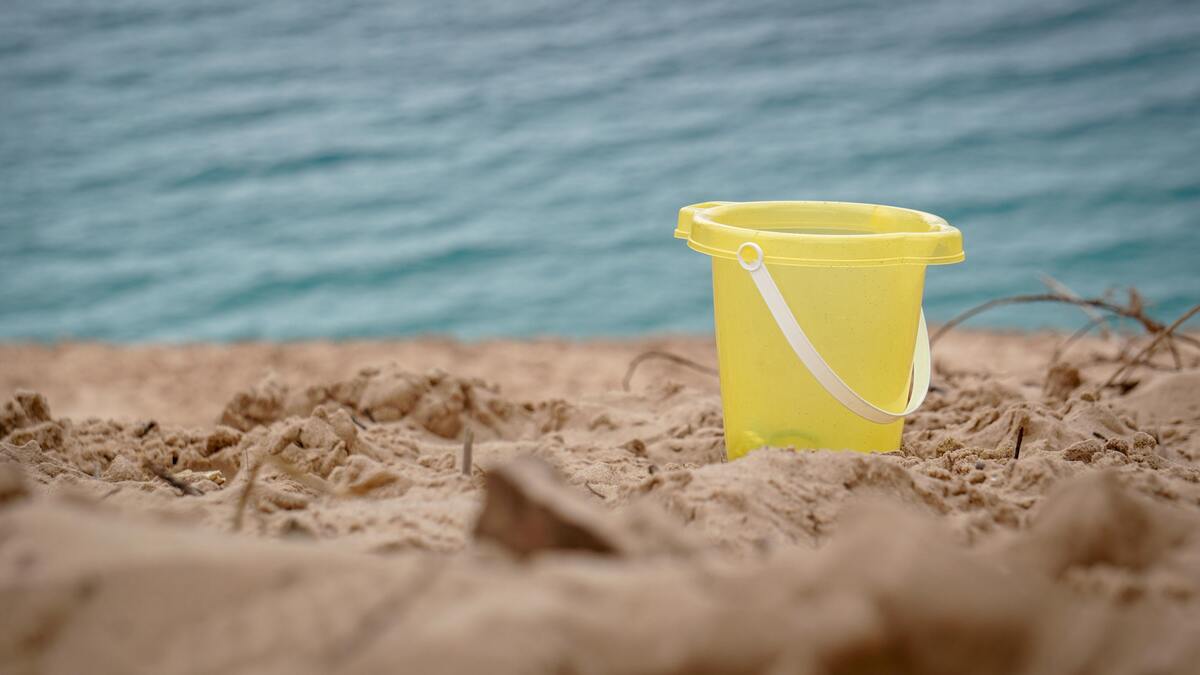 Balde amarelo na areia da praia.