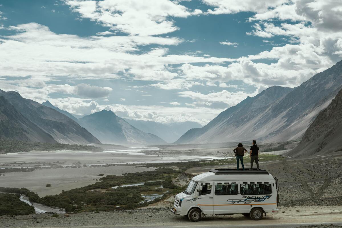 Pessoas em cima de uma van, olhando uma paisagem.