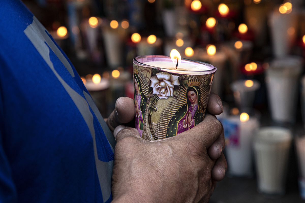 Fiel com vela de Nossa Senhora de Guadalupe nas mãos