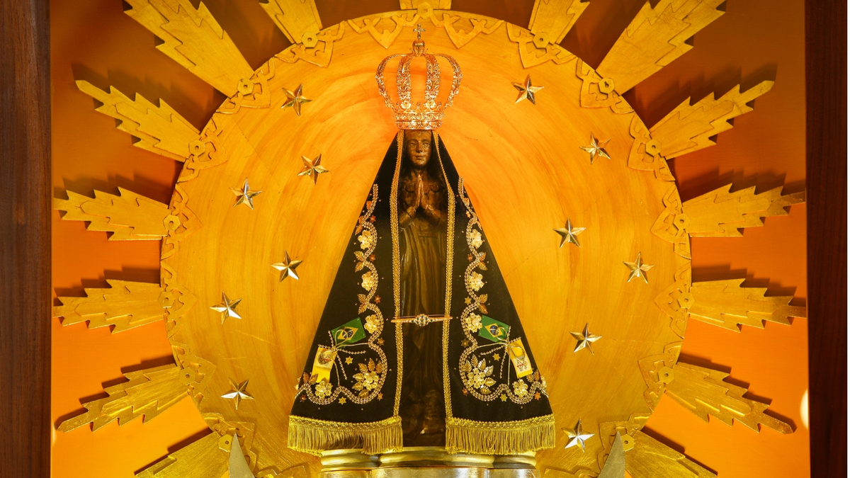 Imagem de Nossa Senhora Aparecida com fundo dourado.