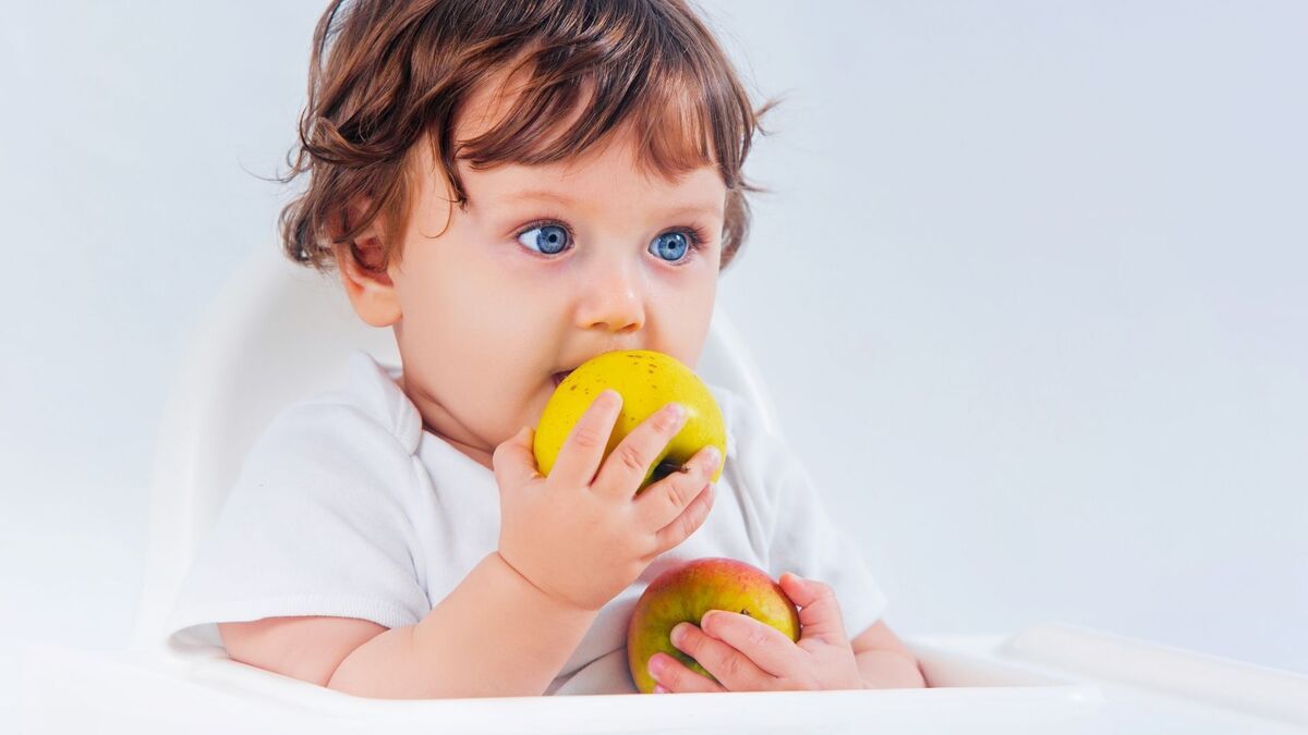 Bebê mordendo uma fruta.