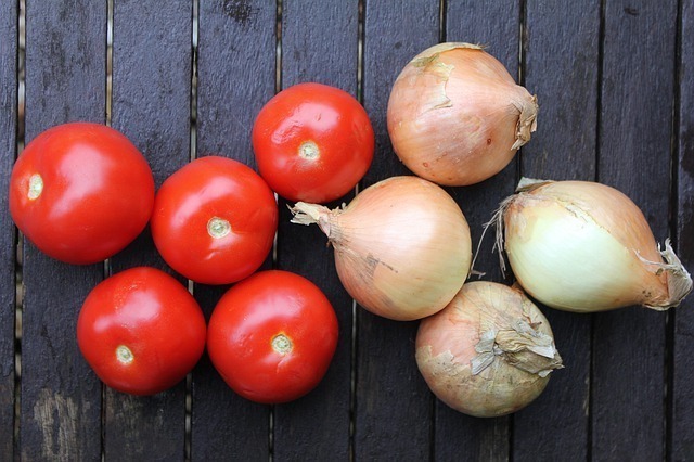 Tomates e cebolas em superfície de madeira