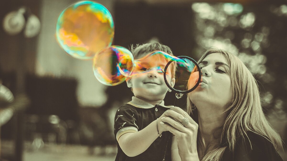 Mulher assoprando bolhas com seu filho.