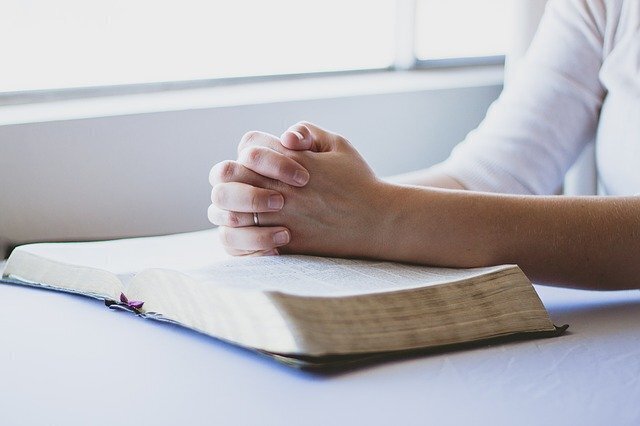 Mãos femininas numa bíblia em sinal de oração