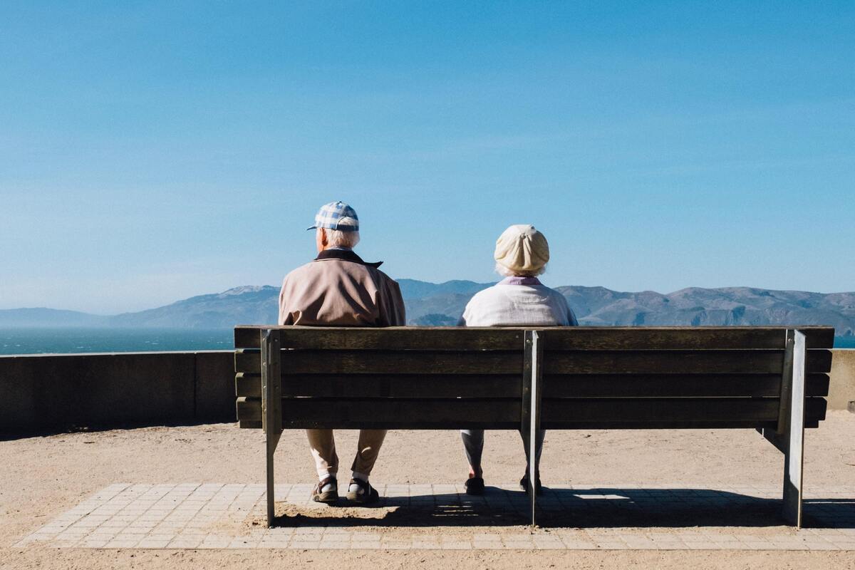 Casal idoso sentado em um banco.