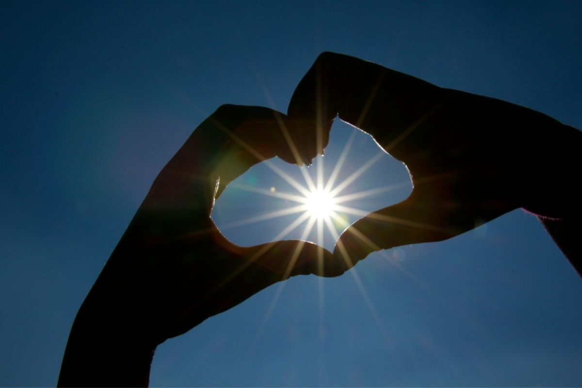 mãos em formato de coração com o Sol no centro