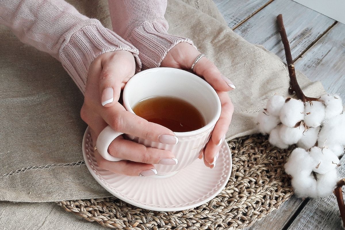 mulher segurando uma xícara de chá nas mãos