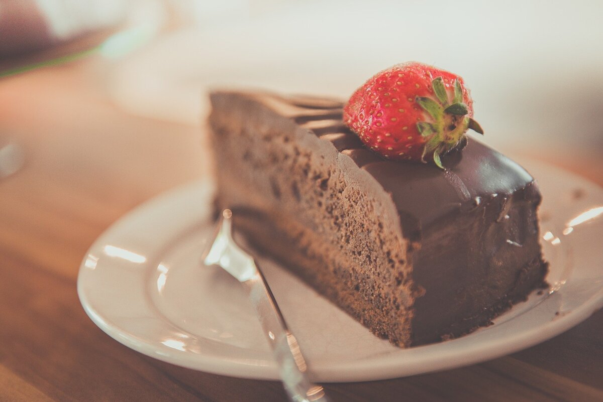 Pedaço de bolo de chocolate com um morango em cima. 