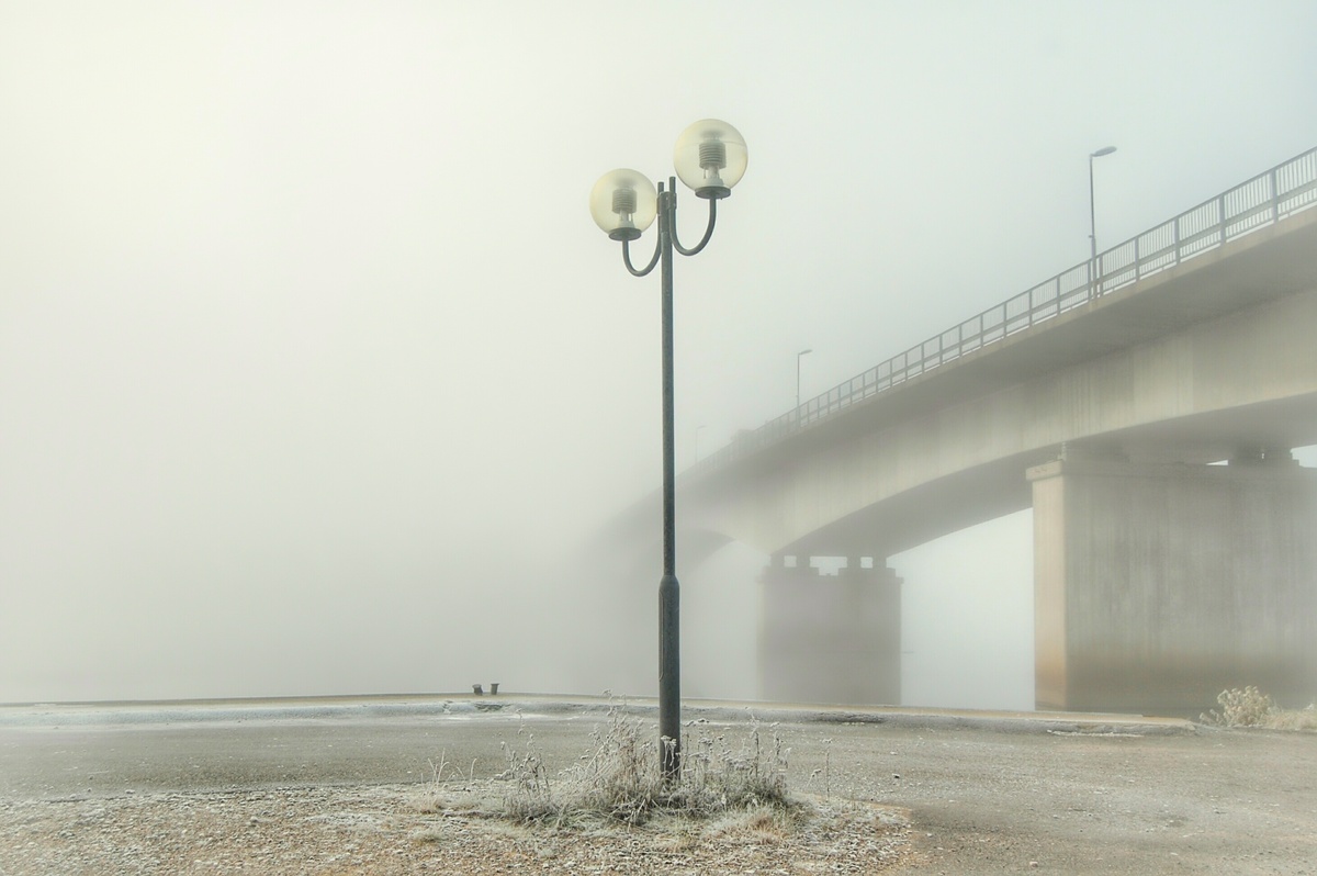 Poste de luz próximo de ponte com névoa