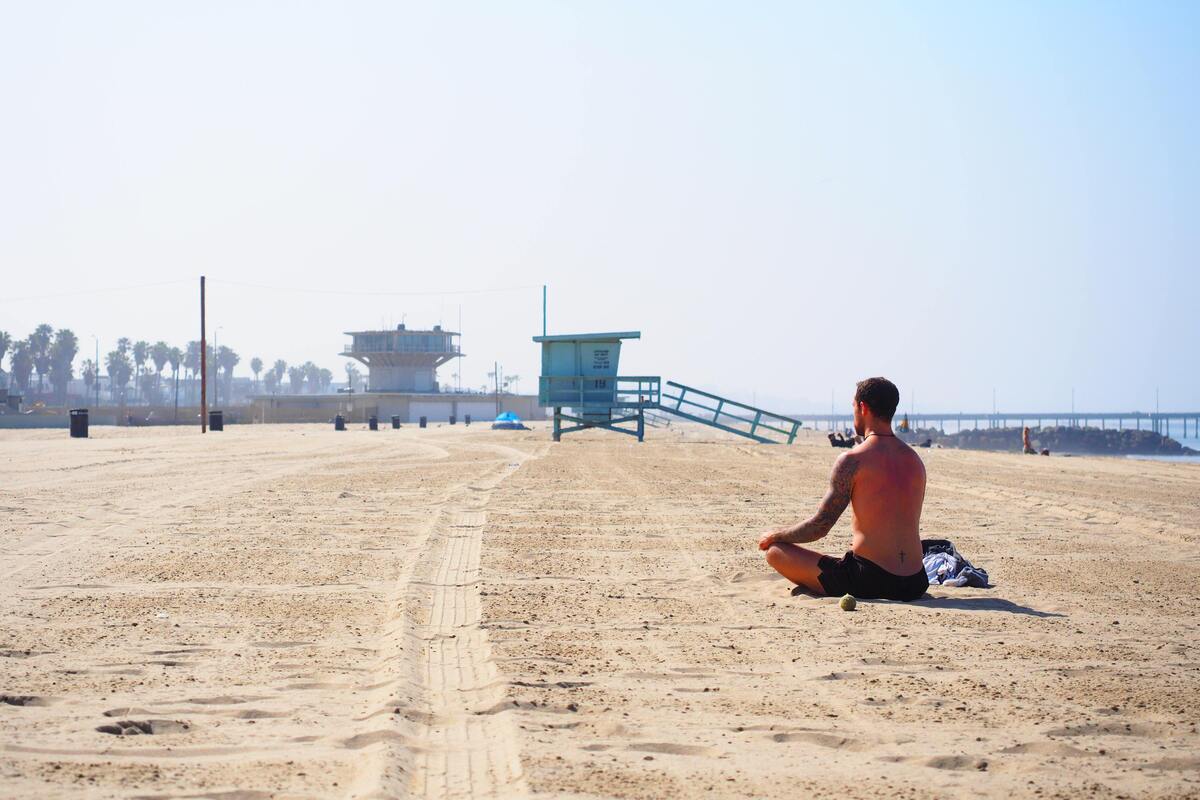 Homem meditando na praia.