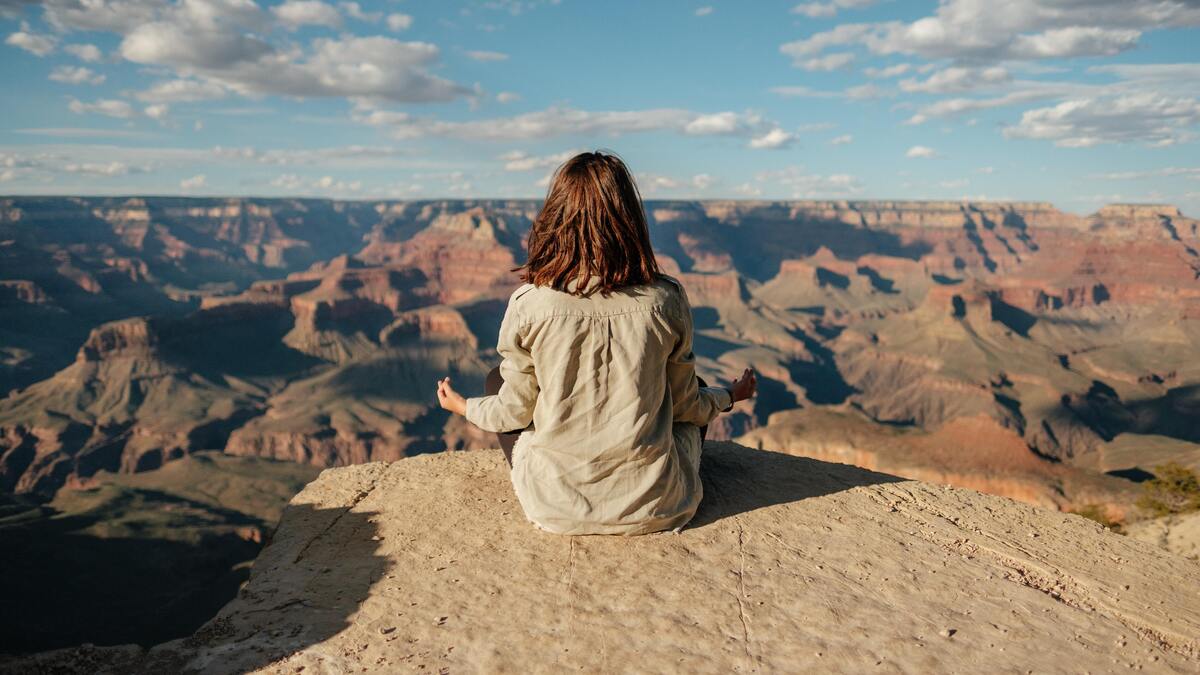 Mulher meditando no topo de uma montanha.