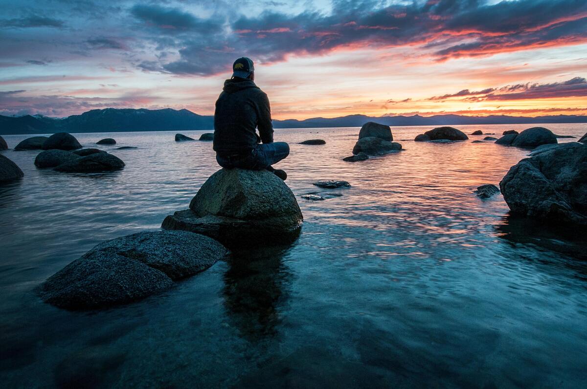 Homem meditando em cima de uma pedra.