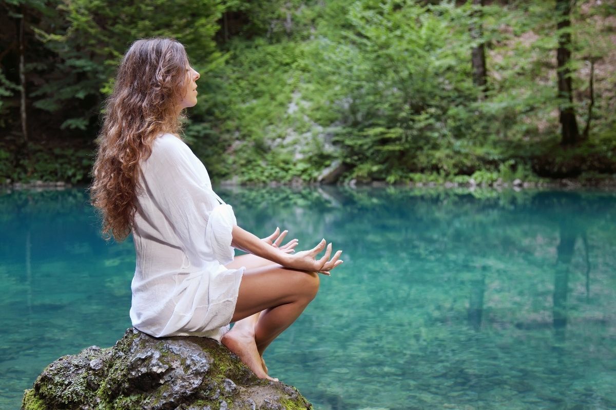 Mulher meditando em um lago azul