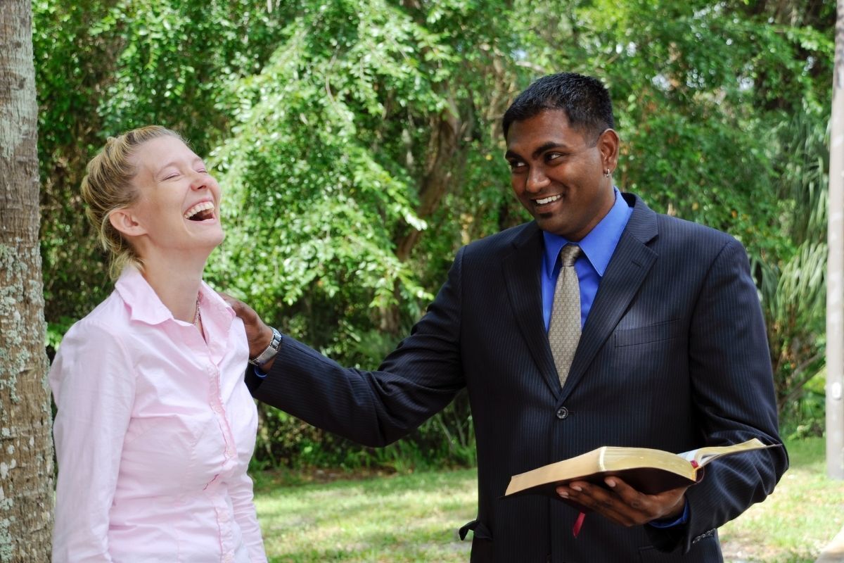 Pastor fazendo revelações com a Bíblia para mulher sorridente