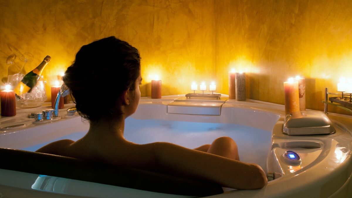 Mulher na banheira com velas.