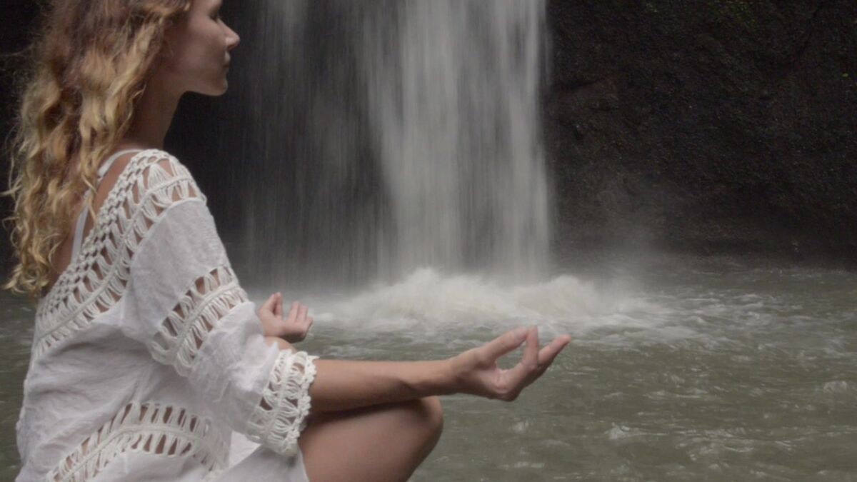Pessoa meditando na cachoeira.