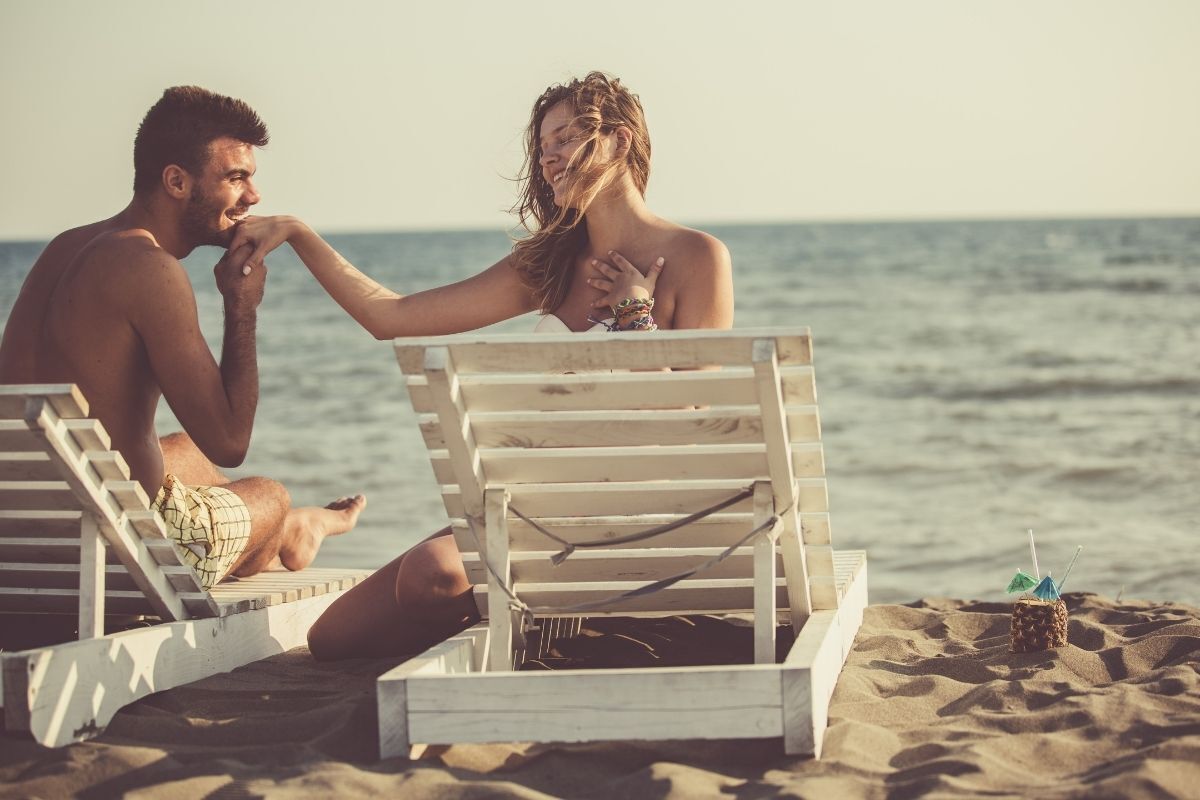 Homem beijando a mão da sua amada na praia