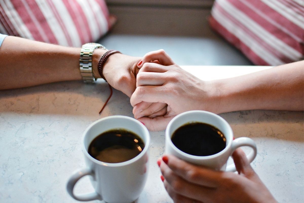 Simpatia para ex arrependido voltar, casal com as mãos entrelaçadas bebendo café