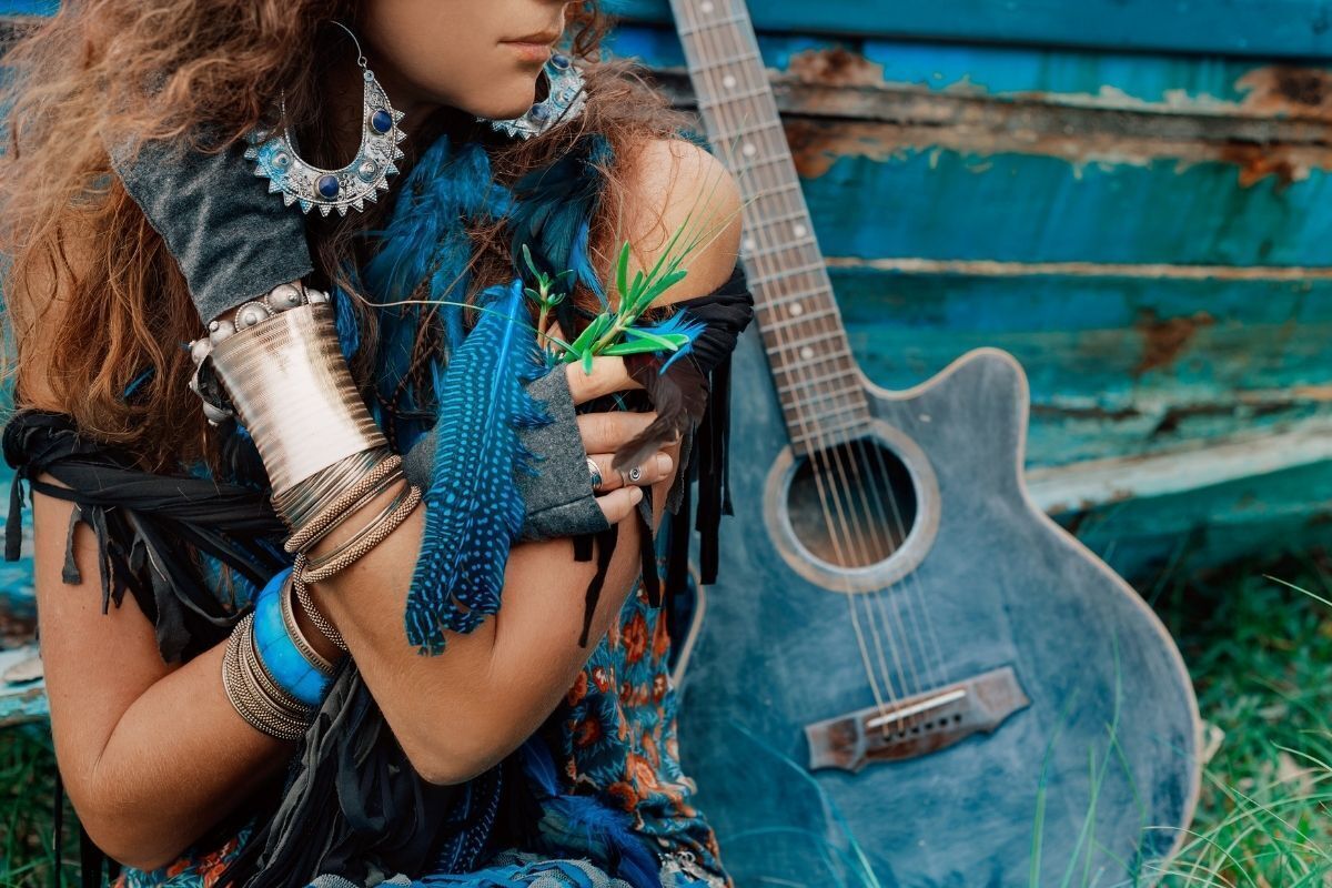 Cigana com brincos e pulseiras grandes na cor azul e prata com violão azul 