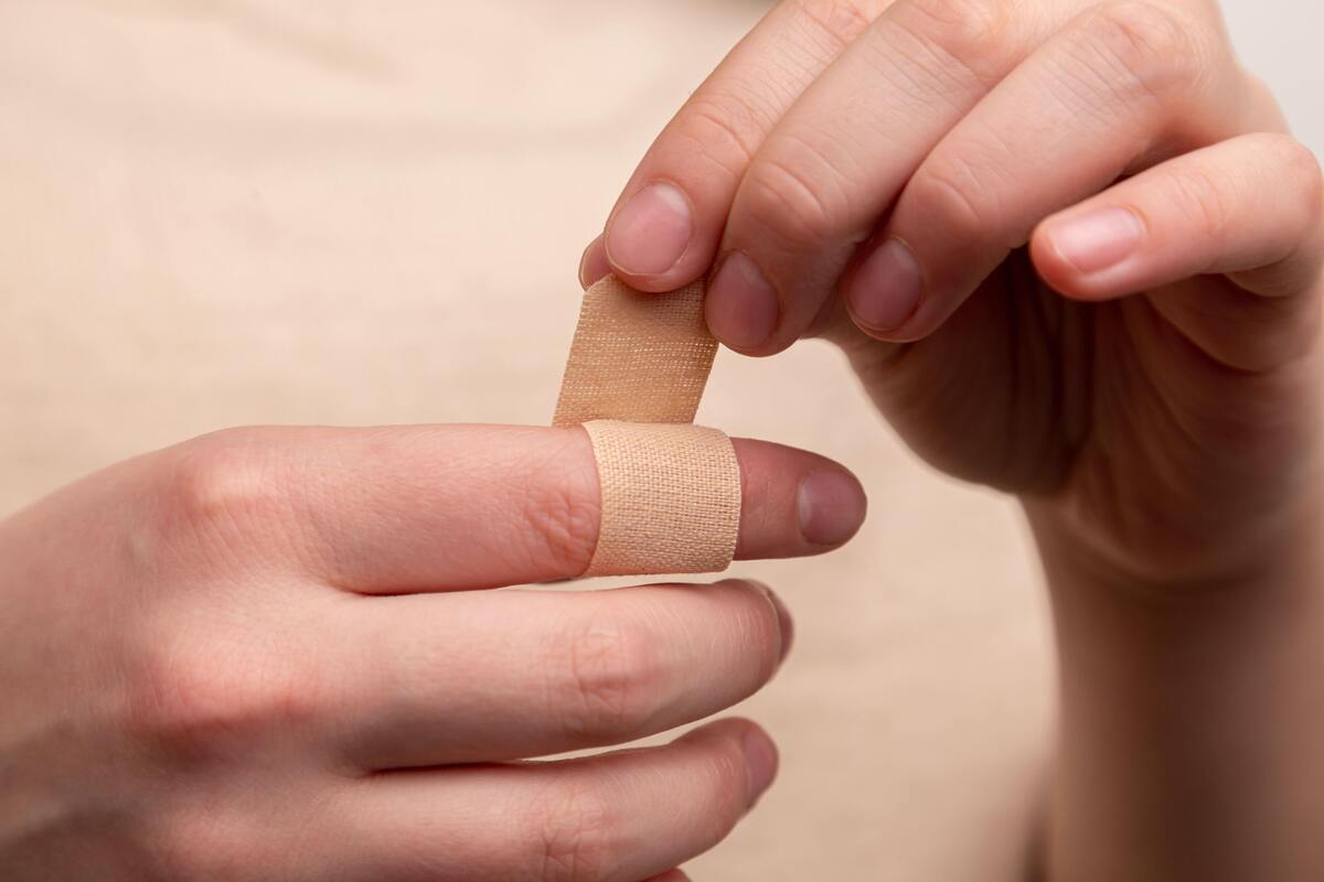Mulher colocando band-aid no dedo.