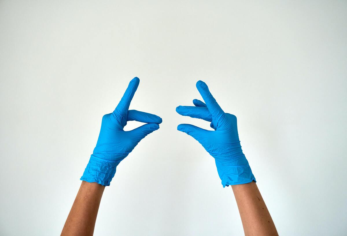 Mãos de mulher usando luvas de plástico.