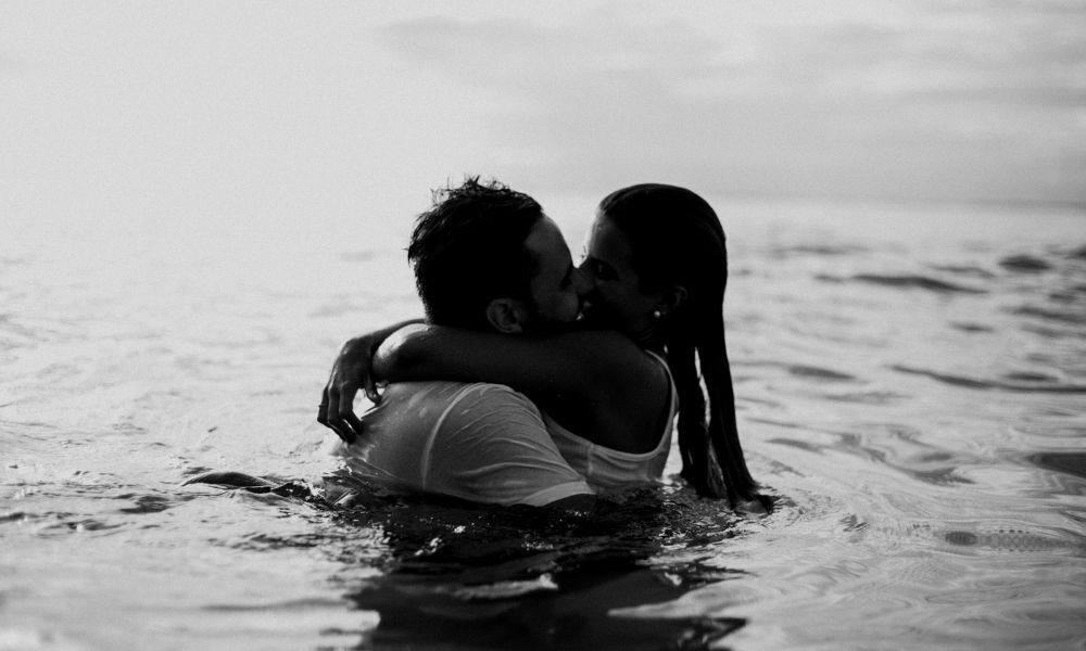 Casal se beijando no mar.