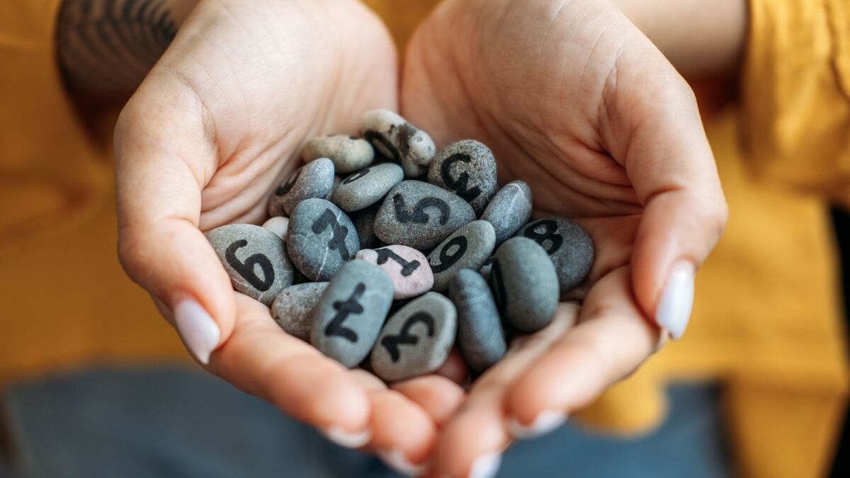 Pedras com números dentro de uma mão.