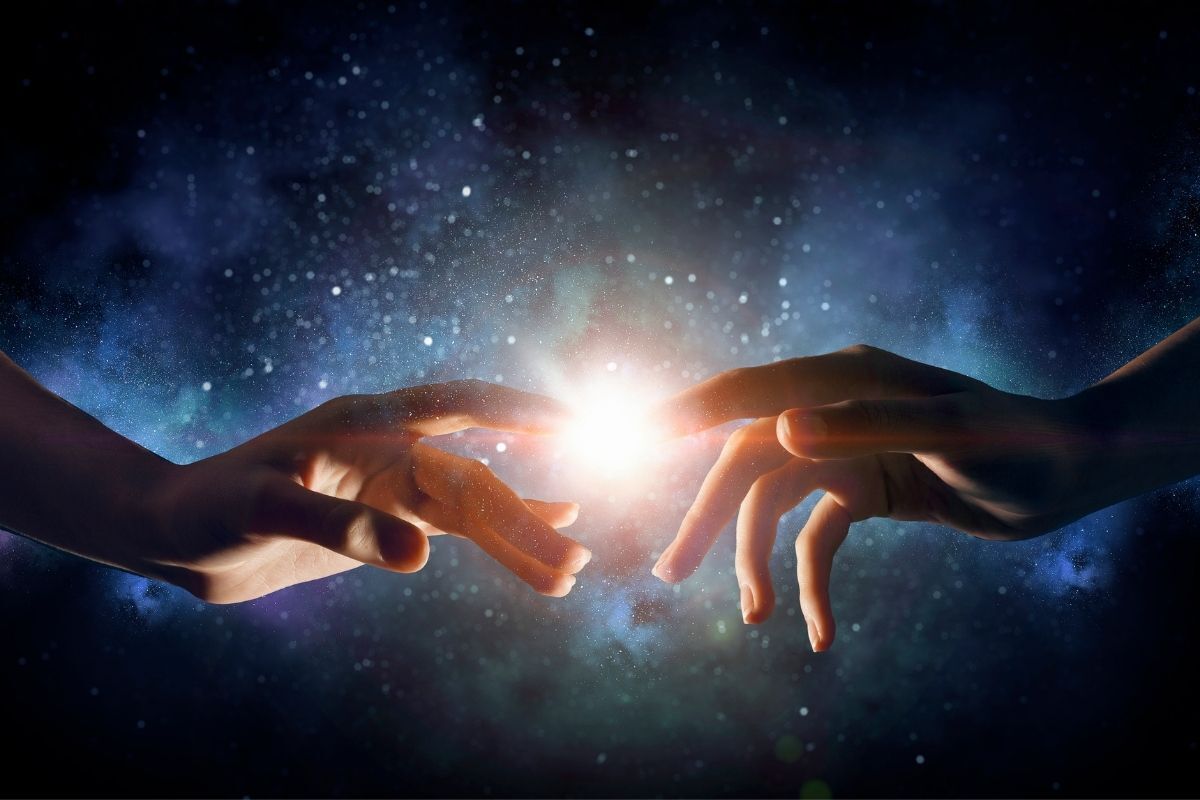 Duas mãos se conectando com um ponto de luz ao fundo