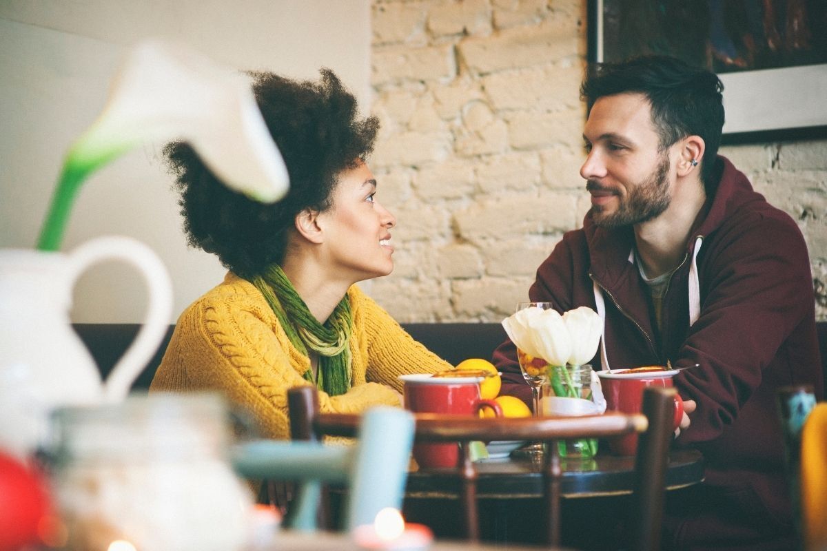 Homem  e mulher sorridentes em uma conversa em um restaurante