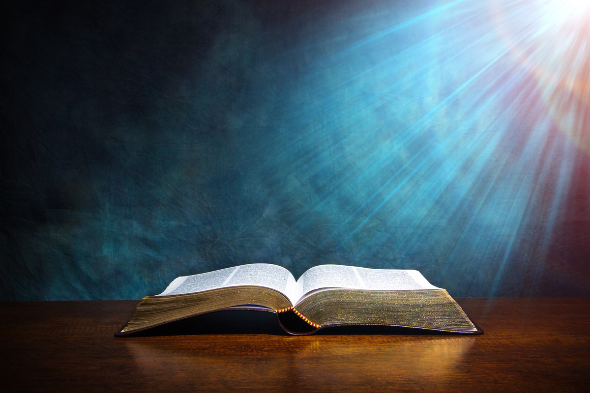 Bíblia em superfície de madeira recebendo luz
