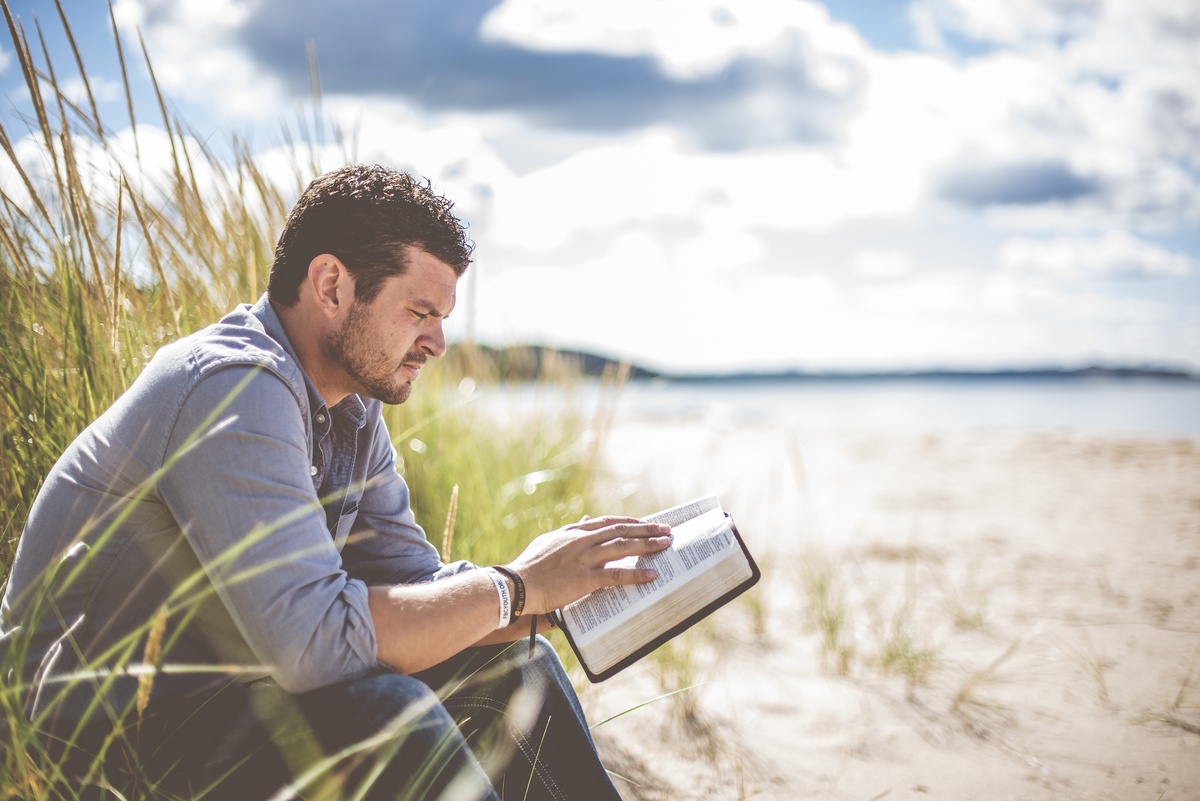Homem lendo a Bíblia na praia