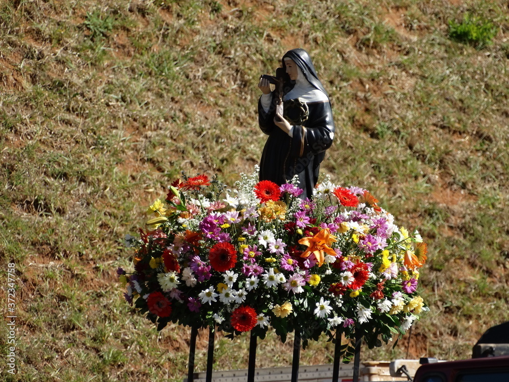 Imagem de Santa Rita de Cássia cercada de flores em um campo aberto