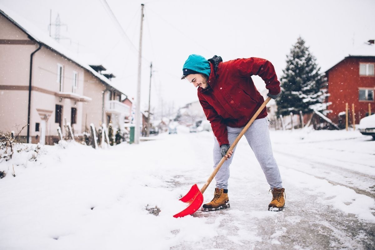 Homem limpando a neve da rua com uma pá