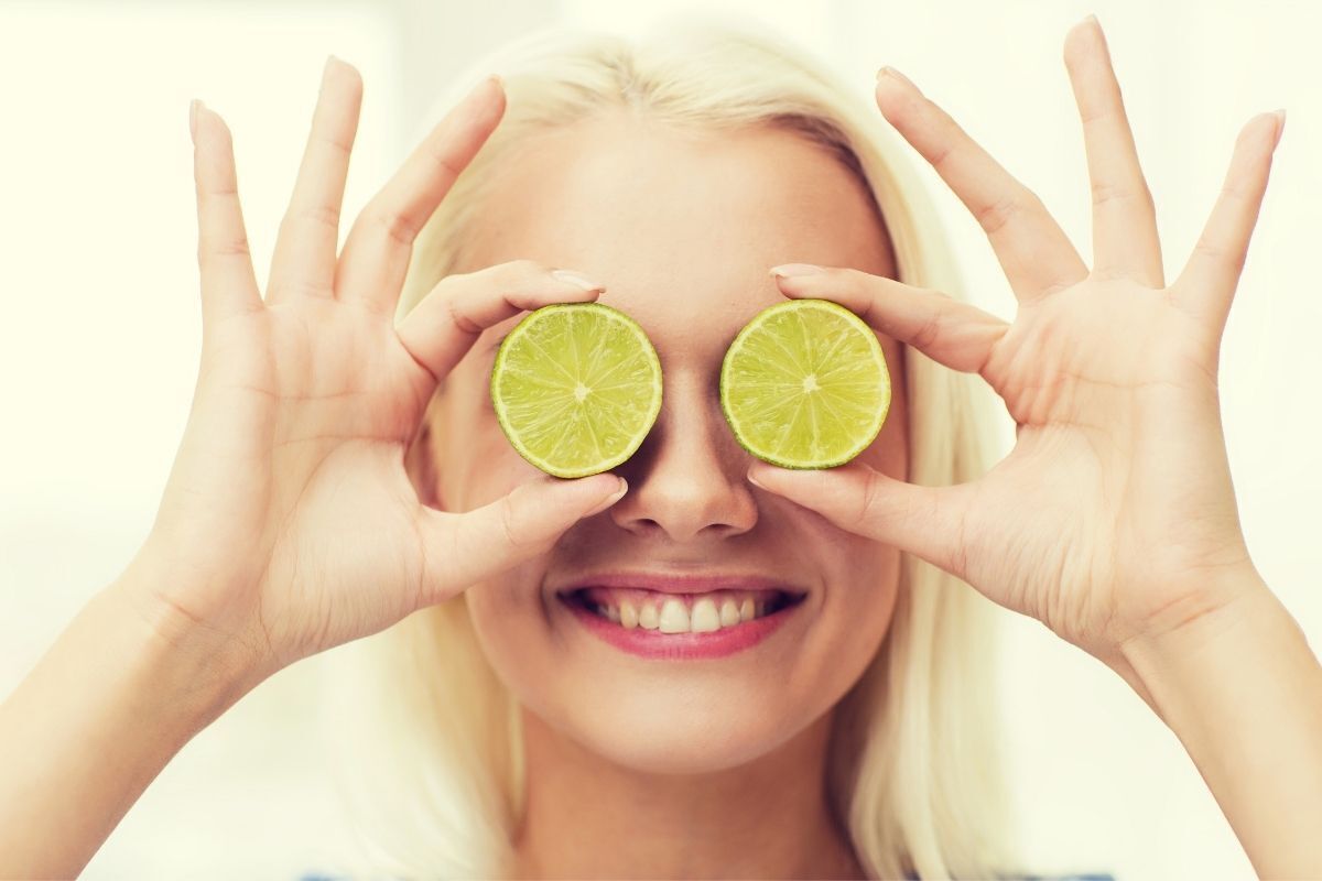 Mulher feliz cobrindo seus olhos com metades de um limão