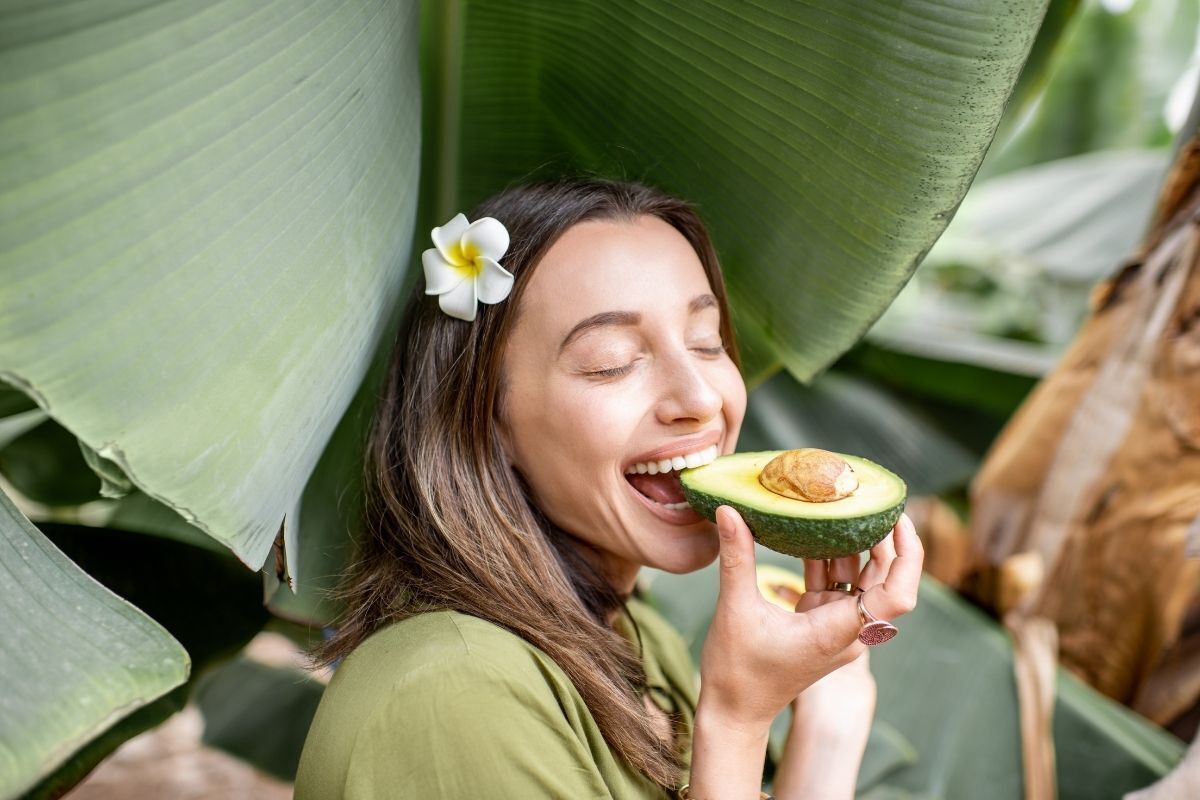 Mulher feliz comendo um abacate