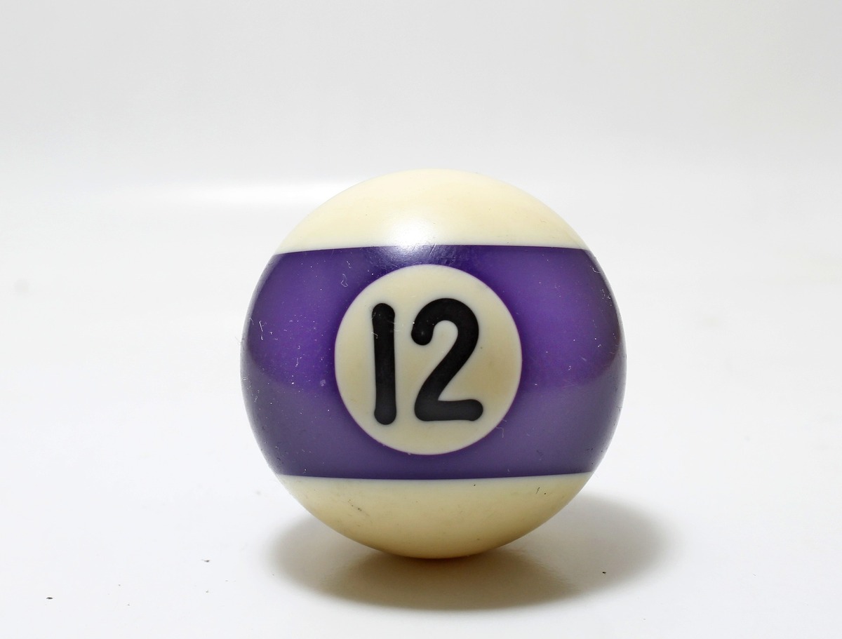 Bola de sinuca branca com listra roxa, e o número 12 gravado ao meio.