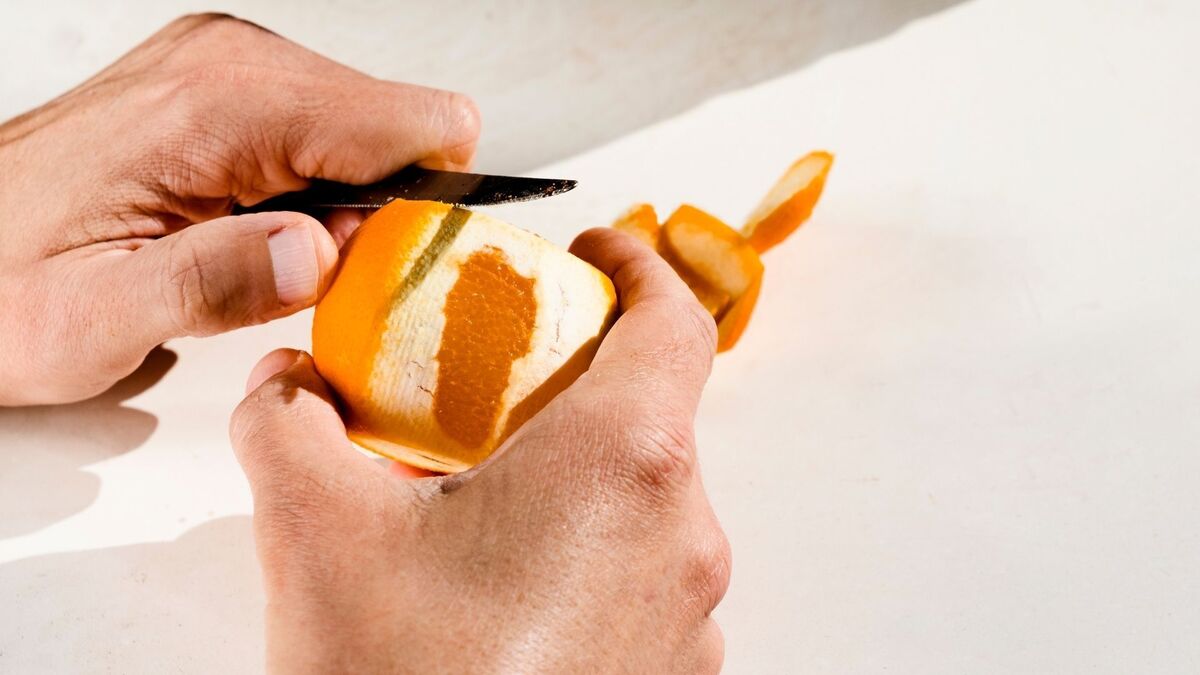 Pessoa descascando laranja.