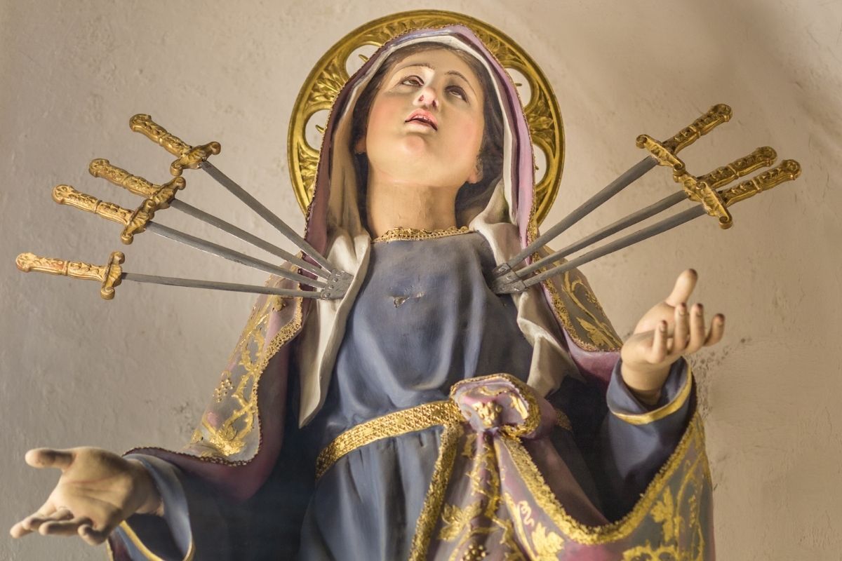 Imagem de Nossa Senhora das Dores olhando para cima, simbolizada por sete espadas cravadas em seu peito