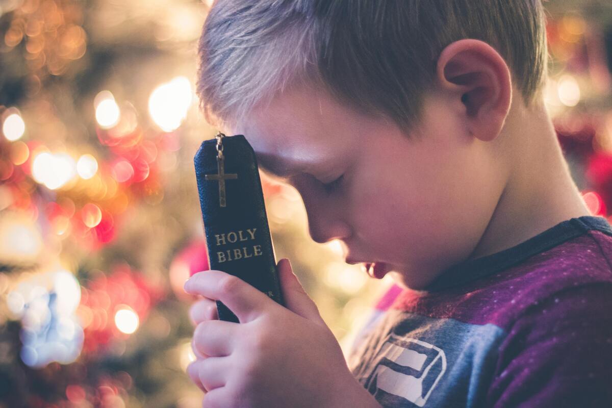 Criança segurando uma bíblia. 