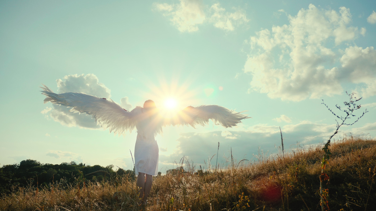 Pessoa correndo para o horizonte enquanto porta asas de anjo nas costas. 