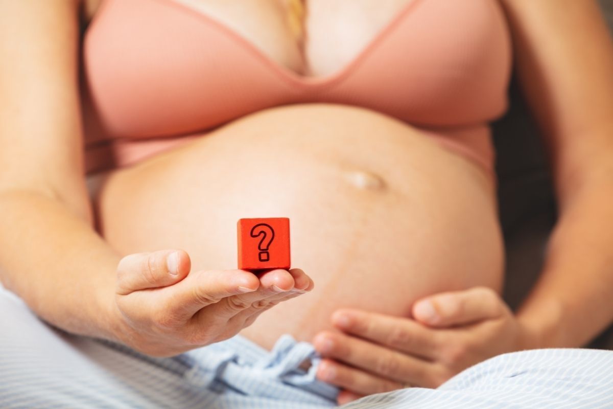 Mulher grávida segurando um símbolo do ponto de interrogação