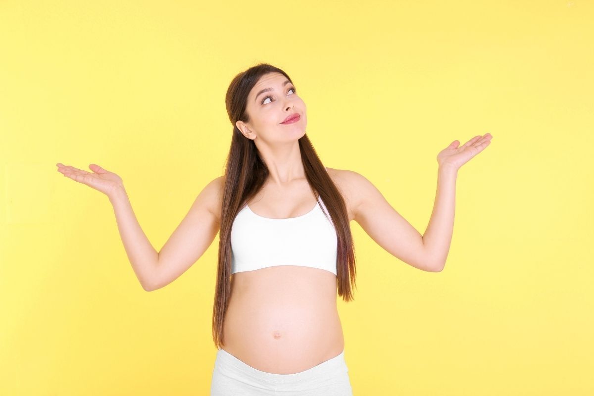 Mulher grávida fazendo o sinal de dúvidas com as mãos
