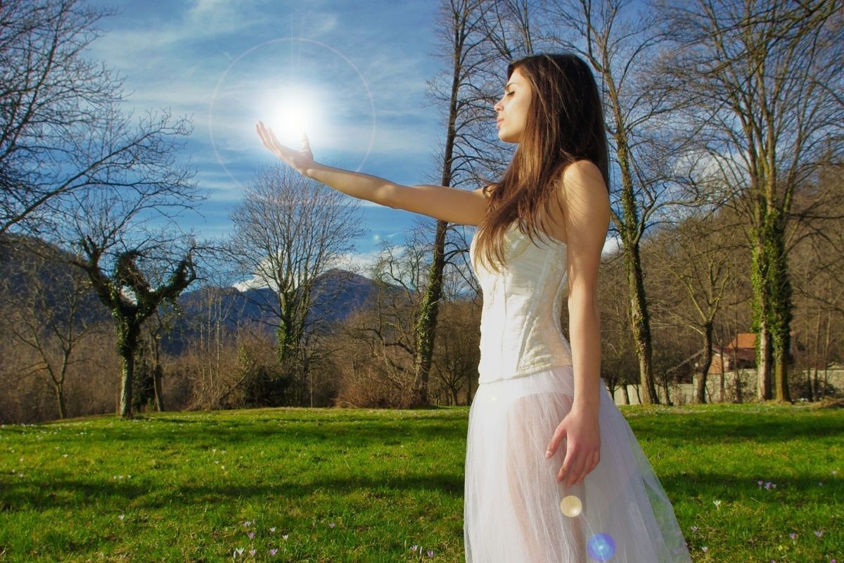 Ilustração de uma pessoa médium, alcançando a luz do sol com uma de suas mãos, vestida de branco