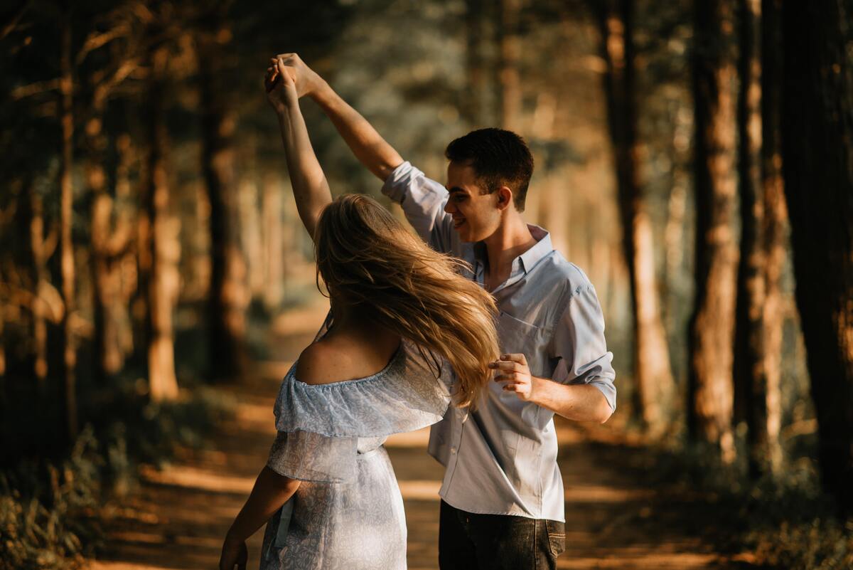 Casal dançando no meio de uma floresta.