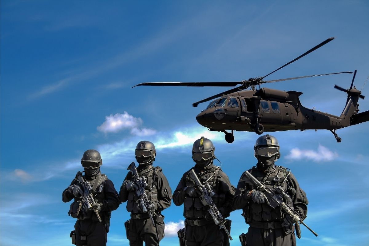 Militares uniformizados e armados. Helicóptero militar no céu azul.