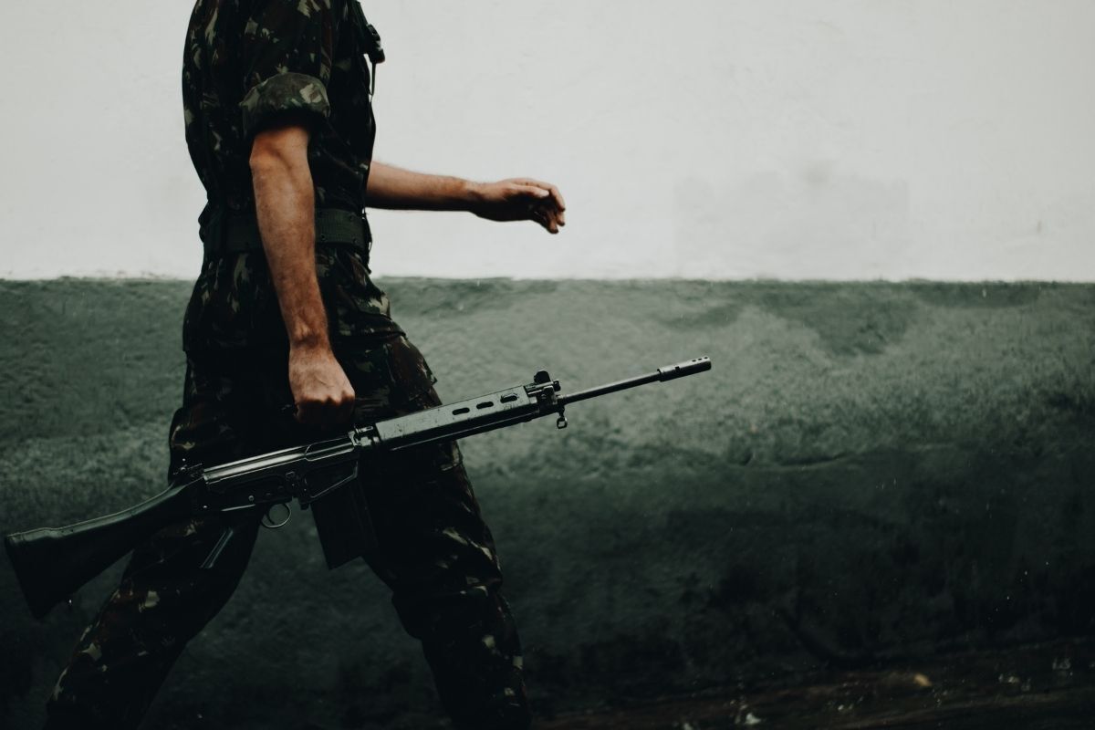 Militar caminhando com uma arma na mão.