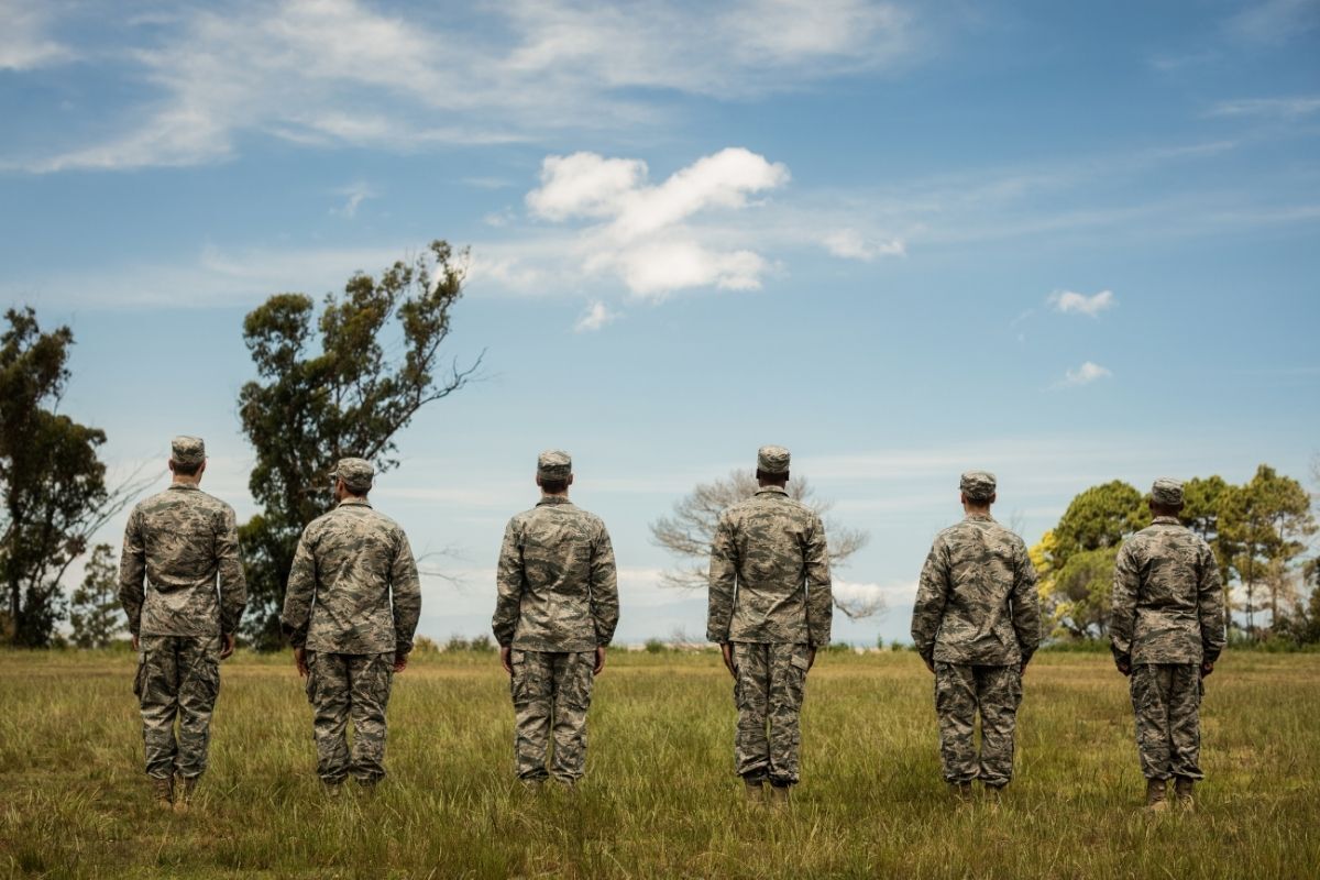 Militares de costas em um campo verde