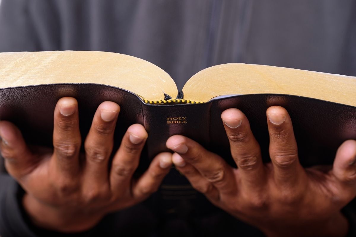 Homem rezando com bíblia.