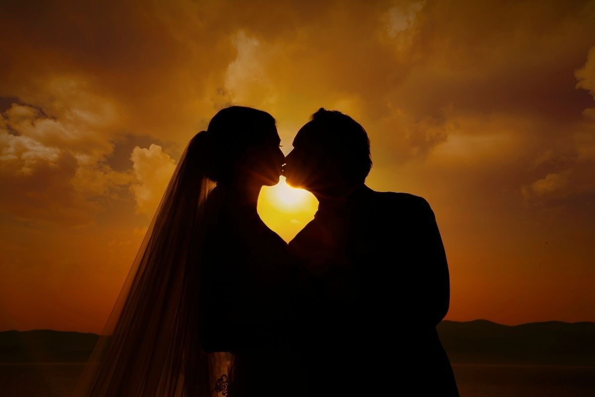 Casal se beijando ao pôr do sol.